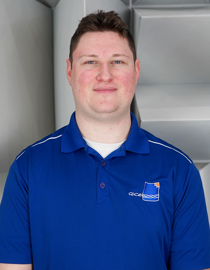 Headshot of ACE Ontario Tech R&D Engineer Eric Whalls in ACE and Ontario Tech University branded blue polo in hemi-anechoic chamber